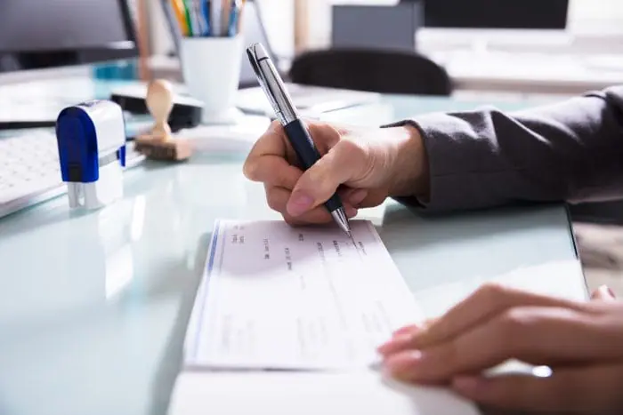 Person writing a cheque at office desk