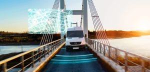 Autonomous van driving across bridge at sunset