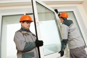 Construction workers installing large glass window frame