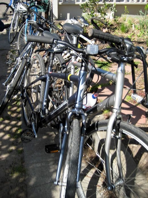 Several bicycles parked closely on pavement.