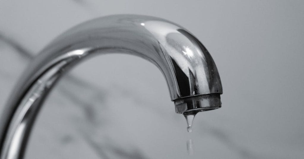 Chrome tap dripping water in bathroom