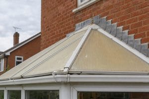 Yellowed polycarbonate conservatory roof showing UV damage and weathered ridge bar