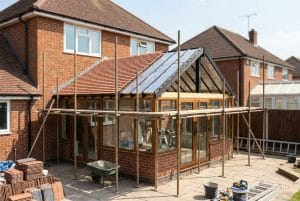 UK conservatory mid-install with scaffolding and partial tiled roof