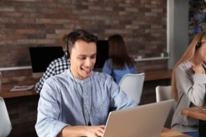 Smiling support agent with a headset working at a laptop in an office